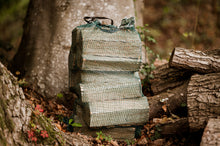 Load image into Gallery viewer, Net sack of firewood in a woodland.
