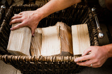 Load image into Gallery viewer, Hands taking a log out of a firewood log basket.
