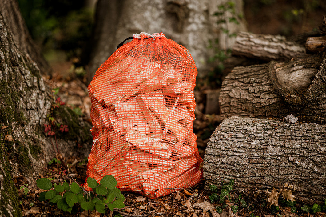 A net bag of hardwood kindling in a woodland.